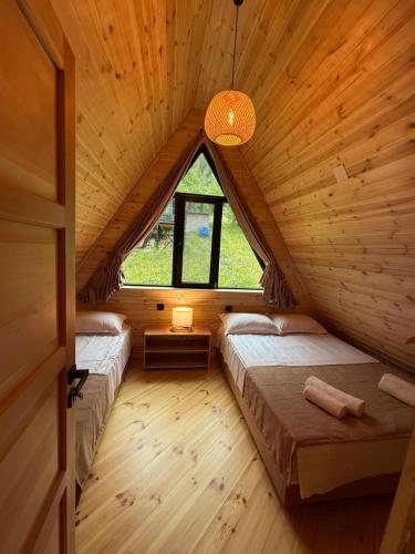 two beds in a wooden room with a window at Horizon Mestia - Premium Chalets With Panoramic Views in Mestia