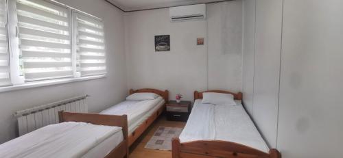 two beds in a room with white walls and windows at 2 BDR Family Apartment In Sarajevo - Free Parking in Sarajevo