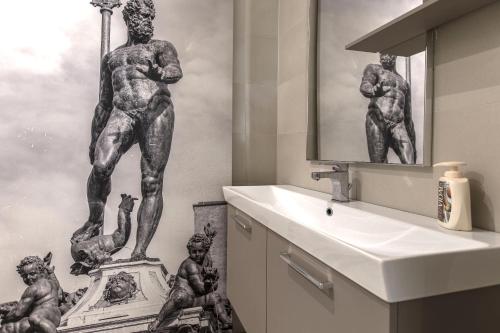 a bathroom with a sink and a sculpture of men at Sun Bologna in Bologna