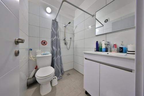 a white bathroom with a toilet and a sink at אירוח סמוך לים התיכון יש מקלט בבניין in Haifa