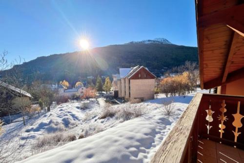 a snow covered yard with the sun shining on a mountain at Charming and bright cottage in Briançon in Briançon