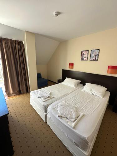 a hotel room with two beds and a window at Tropics Hotel by Aleksis in Sveti Vlas