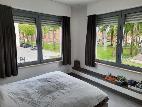a bedroom with large windows and a bed in it at De Reünie - airconditioned duplex appartement & fietsgarage in Langemark