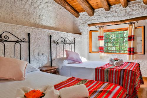 a bedroom with two beds and a window at Cuevas El Moral in Castilléjar