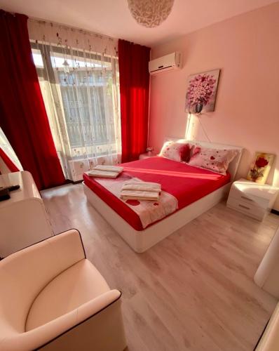 a bedroom with a red bed and a window at Апартамент Green Lines in Primorsko