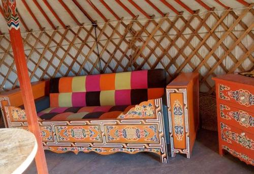 a colorful couch in a yurt with a table at Roulotte tout confort au milieu des animaux in Burthecourt-aux-Chênes