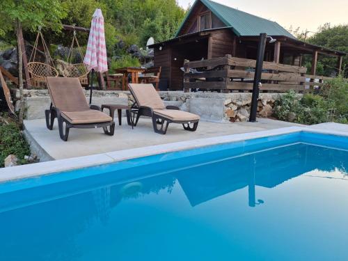 a pool with two chairs and a table and a house at LAKE VIEW PREVLAKA in Cetinje