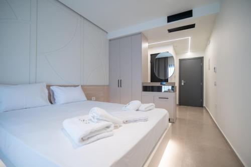 ein weißes Schlafzimmer mit weißen Handtüchern auf einem Bett in der Unterkunft Noema Hotel in Syvota