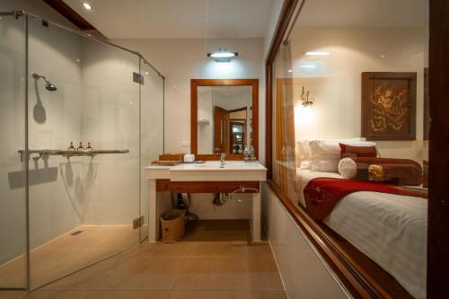 a bathroom with a sink and a bed and a shower at Kodchasri Thani Heritage Collections in Chiang Mai