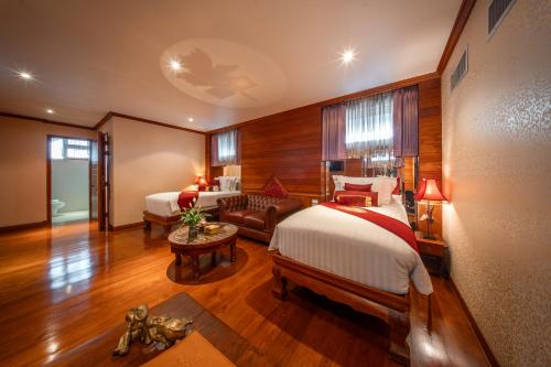 a hotel room with two beds and a couch at Kodchasri Thani Heritage Collections in Chiang Mai