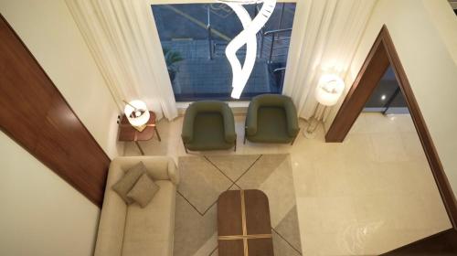 a living room with two green chairs and a window at Sambac hotel in Jeddah