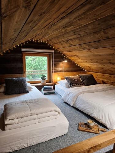 two beds in a room with wooden ceilings at Le Chalet Lasseube in Lasseube