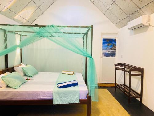 a bedroom with a bed with a blue canopy at Aaliya Bay in Pottuvil