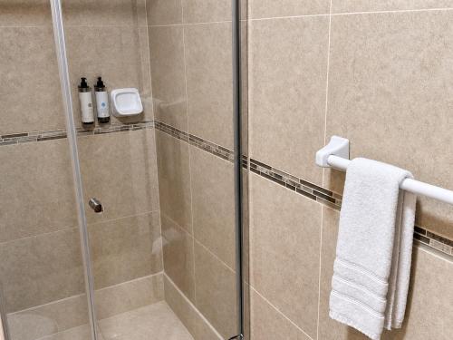 a shower with a glass door with a towel at Hotel Sol Natura in Ollantaytambo