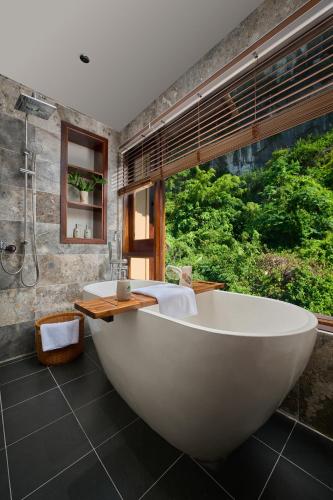 a large bath tub in a bathroom with a window at Hang Múa Ecolodge Ninh Hoà in Ninh Binh
