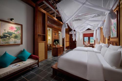 a bedroom with a large white bed and a couch at Hang Múa Ecolodge Ninh Hoà in Ninh Binh