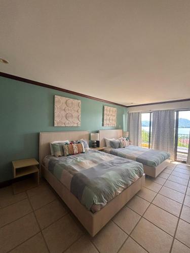 a bedroom with two beds and a large window at Sunset Heights 402 in Playa Flamingo