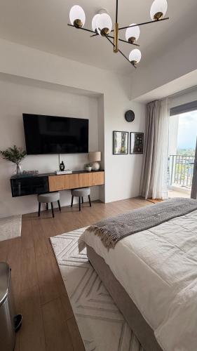 a bedroom with a large bed and a flat screen tv at studio MA-DE cozy Bacolod City in Bacolod