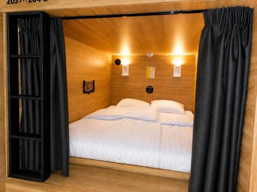 a bedroom with a large bed with black curtains at De Lola Podshotel in The Hague