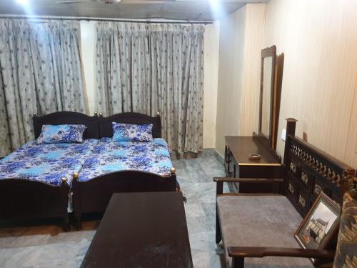 a bedroom with a bed and a dresser and curtains at Hotel Melodyinn in Gujrāt