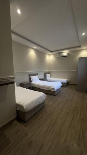 three beds in a room with wooden floors at منتجع وفلل المرفأ ابها in Abha