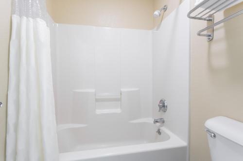 a bathroom with a white shower curtain and a bath tub at Days Inn by Wyndham Simpsonville in Simpsonville