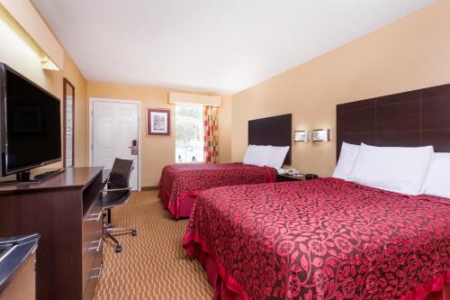 a hotel room with two beds and a flat screen tv at Days Inn by Wyndham Simpsonville in Simpsonville
