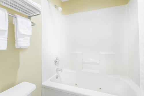 a white bathroom with a tub and a sink at Days Inn by Wyndham Simpsonville in Simpsonville