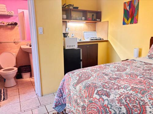 a bedroom with a bed and a bathroom with a sink at Ellen Bay Cottages in Saint Philips
