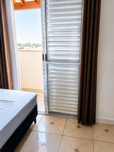 a bedroom with a sliding glass door with a window at Apartamentos-6-3-8 - Pousada Itapetininga in Itapetininga