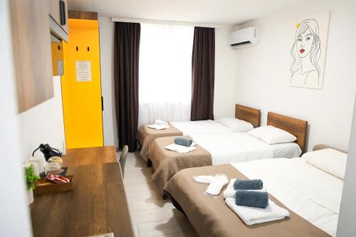 a hotel room with three beds and a window at Nuvelle Boutique Hotel in Prizren