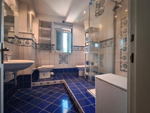 a bathroom with a blue tiled floor and a toilet and sink at La casetta di Daniela in Sabaudia