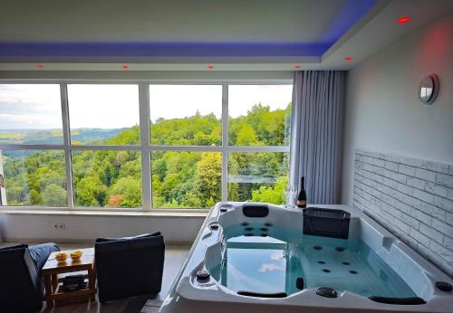 a large bath tub in a room with a large window at Private wellness with panoramic view, sauna & jacuzzi in Maribor