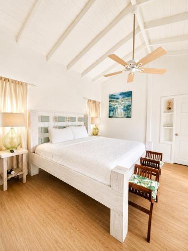a white bedroom with a large bed and a ceiling fan at 3 Bedroom Villa with Pool and Ocean Views in Cap Estate