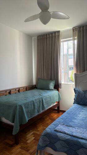 a bedroom with two beds and a ceiling fan at Quarto privativo confortável próximo a ufba, praia, comercio e zoológico in Salvador