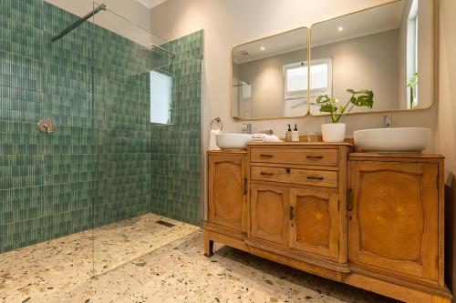 a bathroom with two sinks and a shower with a mirror at Lagoon View Cottage in Knysna