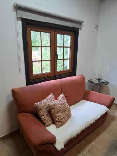 a couch with two pillows sitting in a room with a window at Cantinho do Lello in Bragança