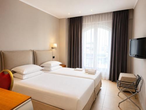 ein Hotelzimmer mit einem großen Bett und einem Fernseher in der Unterkunft Hotel Iliana in Filippiada