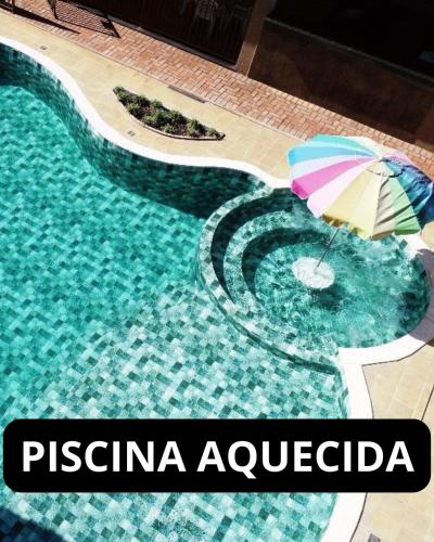 a swimming pool with an umbrella in the water at POUSADA JARDIM BOTANICO in Olímpia