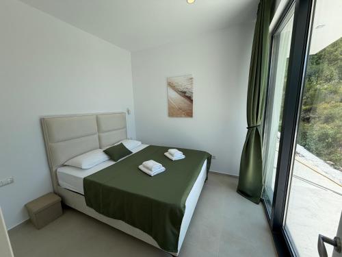 a bedroom with a bed and a large window at Green House in Perazića Do