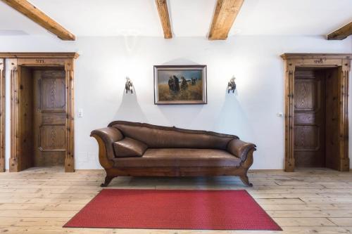 a brown leather couch in a room with a red rug at Hotel Senningerbräu in Bramberg am Wildkogel