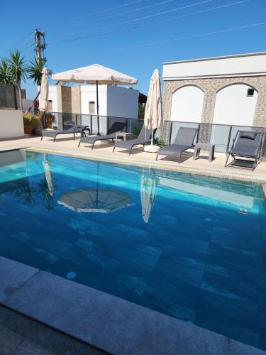 a swimming pool with two chairs and an umbrella at Ilya Apart 1 in Bodrum City