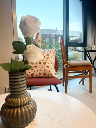 a vase with a flower on a table with a chair at Brightside Suite in Kristiansand