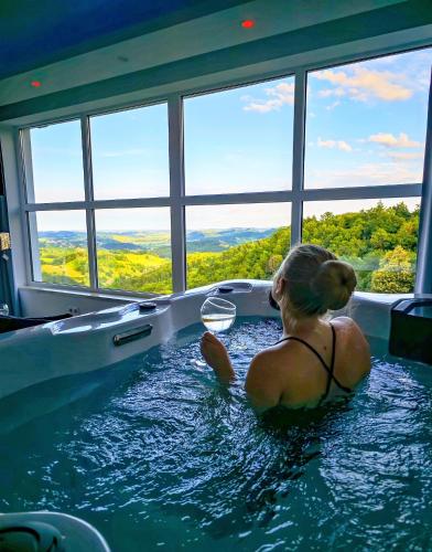 a woman sitting in a hot tub in a room at Private wellness with panoramic view, sauna & jacuzzi in Maribor
