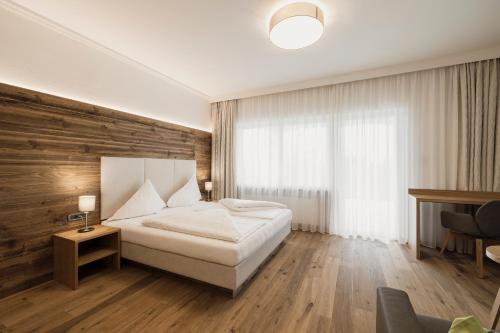 a bedroom with a white bed and a wooden wall at Hotel Greifenstein in Terlano