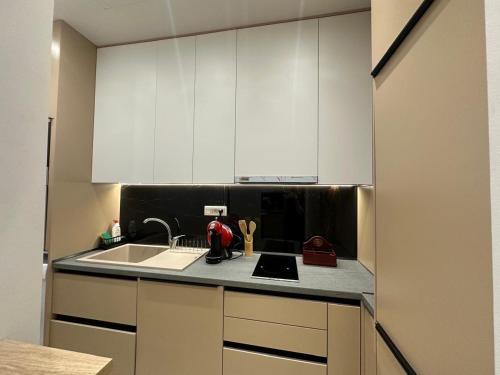 a kitchen with white cabinets and a sink at Ionian Rooms in Vlorë