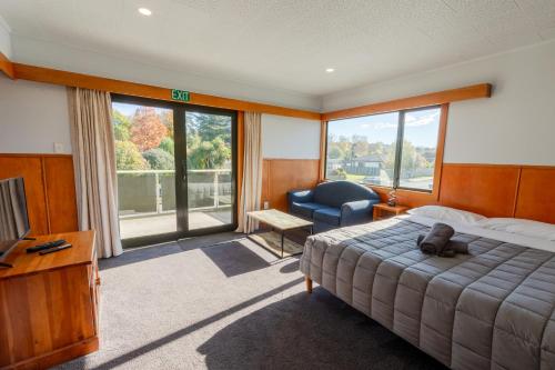 a bedroom with a bed and a chair and a television at Geraldine Motels in Geraldine