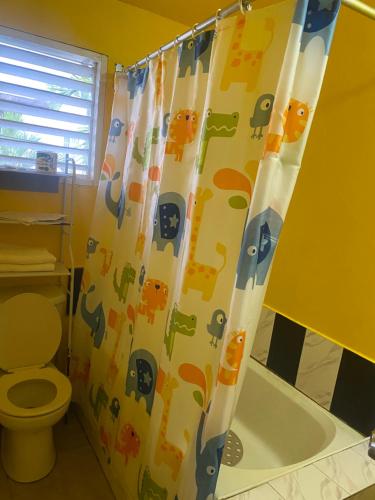 a bathroom with a shower curtain with animals on it at Rooms on the 7 Mile in Negril