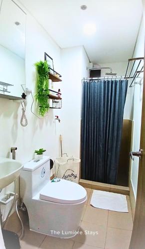 a bathroom with a toilet and a black shower curtain at The Lumière Stays Cozy Mallside Boutique Haven in Trece Martires