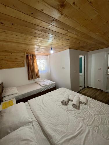 a bedroom with two beds and a wooden ceiling at Bujtina Sherifaj in Valbonë